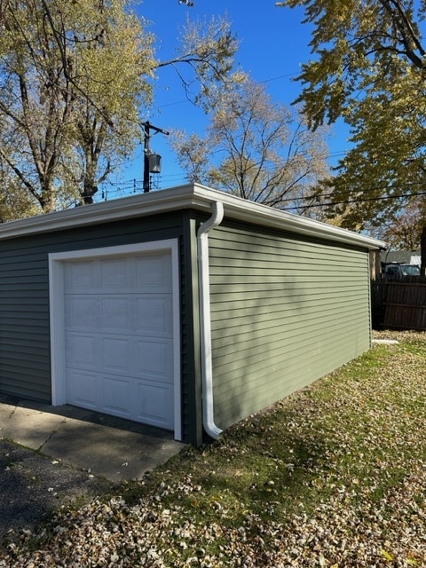 A garage with a green siding and a garage door.